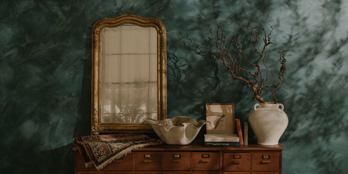 Antique rug, sculptural vessels and gilt mirror arranged on a vintage wooden cabinet